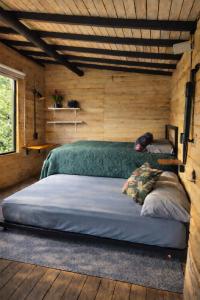 a bedroom with two beds in a log cabin at Refugio La Tángara del Río in Cocorná +12 photos