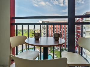 a table with two cups on a balcony with chairs at Mactan Cebu Cozy Relaxing Studio with Pool View Balcony in Pajak