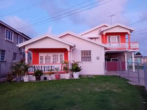 a white and orange house with a green yard at Joyville in Bridgetown