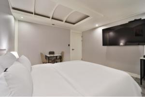 a white bedroom with a bed and a table at Page 9 Hotel in Seoul