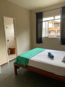 a bed sitting in a room with a window at Quarto no centro in Sete Lagoas