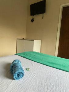 a blue towel laying on a bed with a green blanket at Quarto no centro in Sete Lagoas