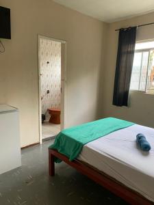 a bedroom with a bed and a door to a bathroom at Quarto no centro in Sete Lagoas