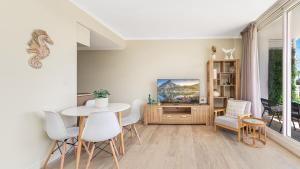 a living room with a table and chairs and a tv at Peacock Hideaway in Ettalong Beach