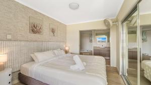 a bedroom with a large white bed and a bathroom at Peacock Hideaway in Ettalong Beach