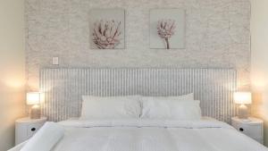 a bedroom with a white bed with three pictures on the wall at Peacock Hideaway in Ettalong Beach +15 photos