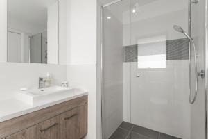 a white bathroom with a sink and a shower at The Lavender House in Gledswood Hills +8 photos