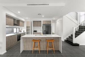 a kitchen with a island and two bar stools at The Lavender House in Gledswood Hills