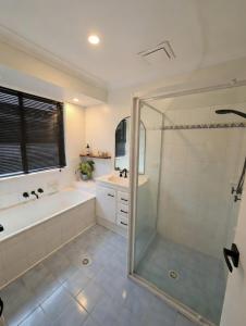 a bathroom with a shower and a tub and a sink at Barefoot at Sunrise Guest Suite in Byron Bay