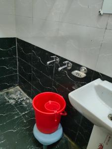 a red bucket sitting next to a sink in a bathroom at Hotel vivekanand in Badrinath