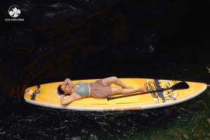 a woman laying on a paddle board in the water at Framstay Mây Sườn Đông in Ðại Từ
