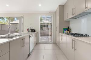 a white kitchen with a sink and a stove at Manning the Waves in Kiama