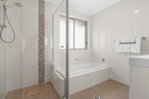 a white bathroom with a tub and a shower at Manning the Waves in Kiama +22 photos
