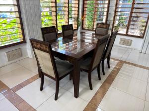a dining room table and chairs in a room with windows at Bua Bed & Breakfast in Nadi