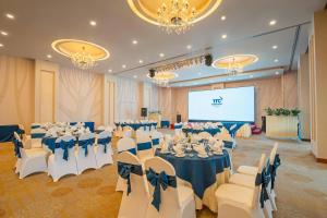 ein Festsaal mit Tischen, Stühlen und einer Leinwand in der Unterkunft TTC Hotel - Ngoc Lan in Da Lat