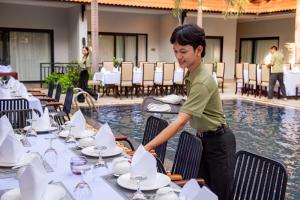 a man setting up a table at a restaurant at The Sears Residence Siem Reap in Phumĭ Réach Born (2) +81 photos