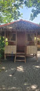 a small hut with a roof on top of it at Mananambal Beach Huts - Hut 2 in Nagbalaye