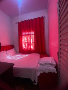 a room with a bed and a red window at Quarto para temporada in Goiânia