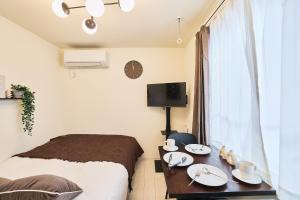 a bedroom with a bed and a table with plates on it at Reberty Haneda in Tokyo