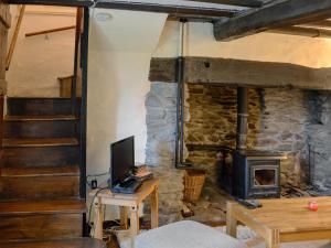a living room with a stone fireplace and a television at Crogen Bryn Awel in Llandrillo