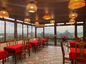 a dining room with red tables and chairs and windows at Tam Coc Vivana Hotel in Ninh Binh