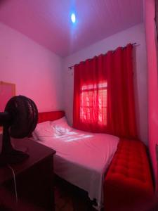 a bedroom with a bed with a red curtain at Quarto para temporada in Goiânia +1 photo