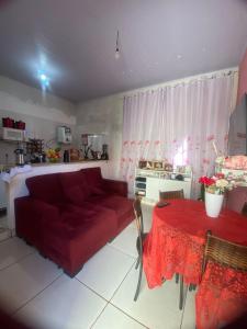 a living room with a red couch and a table at Quarto para temporada in Goiânia