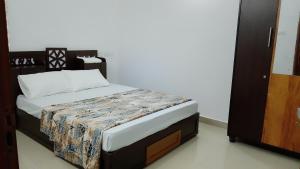 a small bed in a room with a white wall at Haya podes in Vypīn