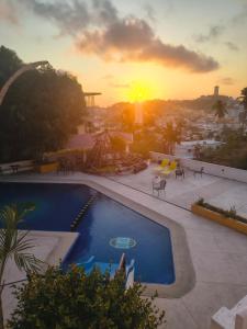 a sunset over a swimming pool on top of a building at Departamento Acapulco tres mares in Acapulco