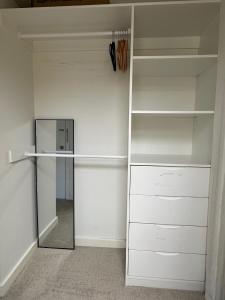 a closet with white shelves and a mirror at A cozy room with ensuite in Springvale, in a shared accommodation in Springvale