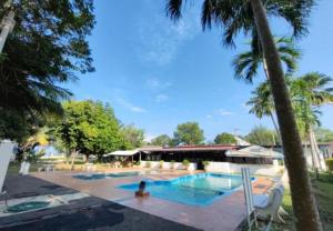 a pool with palm trees and a person sitting next to it at Hotel Green Town Port Dickson in Port Dickson