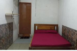 a small bedroom with a bed with a red blanket at Penginapan Joko Samudro in Baron