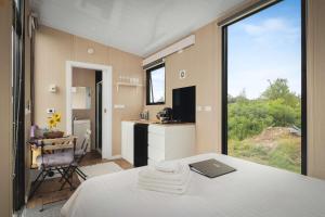 a room with a bed and a kitchen with a large window at Revillaging Project by Tiny Away in Boneo