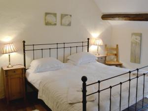 a bedroom with a large bed with white sheets and two lamps at Crogen Bryn Awel in Llandrillo