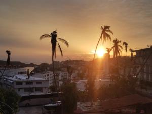 a sunset over a city with palm trees at Departamento Acapulco tres mares in Acapulco