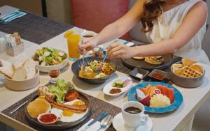 a woman sitting at a table with breakfast foods at Dusit Princess Chiang Mai in Chiang Mai
