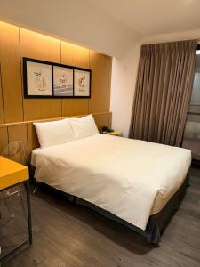 a hotel room with a large bed with white sheets at 逢甲25行館Fengjia 25 Hotel in Taichung