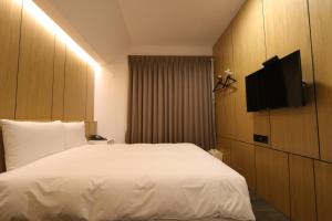 a hotel room with a bed and a flat screen tv at 逢甲25行館Fengjia 25 Hotel in Taichung