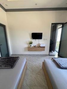a bedroom with two beds and a flat screen tv at Muối Hồng Homestay in Ấp Tân Hà