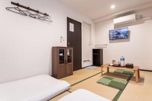 a room with a bed and a table and a tv at Saikou in Osaka
