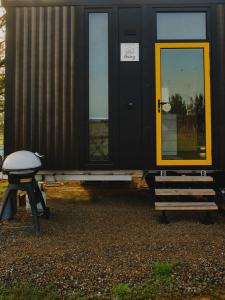 a black house with a yellow door and a bench at Sunset Tiny House at Bluebush Estate X by Tiny Away in Rothbury