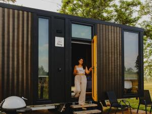 a woman standing in the doorway of a tiny house at Sunset Tiny House at Bluebush Estate X by Tiny Away in Rothbury