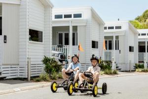 two young boys riding on tricycles down a street at Tasman Holiday Parks - North Star in Hastings Point