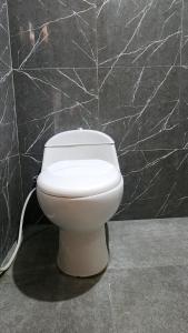 a white toilet in a bathroom with a black wall at Qinoz Villaz in Kedungwaru +17 photos