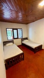 two beds in a room with a wooden ceiling at Alex s Cottage in Kandy