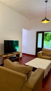 a living room with a couch and a tv at Alex s Cottage in Kandy