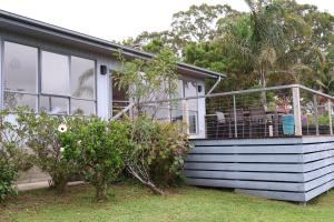a house with a screened in porch on the side of it at Serenity House in Mallacoota