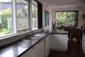 a kitchen with white cabinets and a sink and windows at Serenity House in Mallacoota