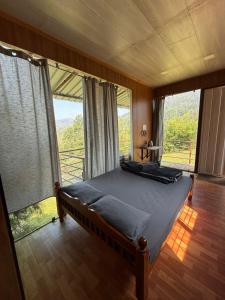 a bedroom with a bed in a room with large windows at Mad & Nomad Backpackers Hostel in Coonoor