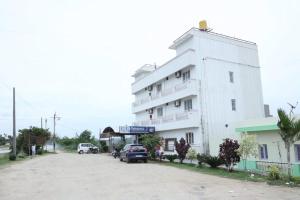 a white building with cars parked in front of it at R R Paradaise in Pūtalapattu